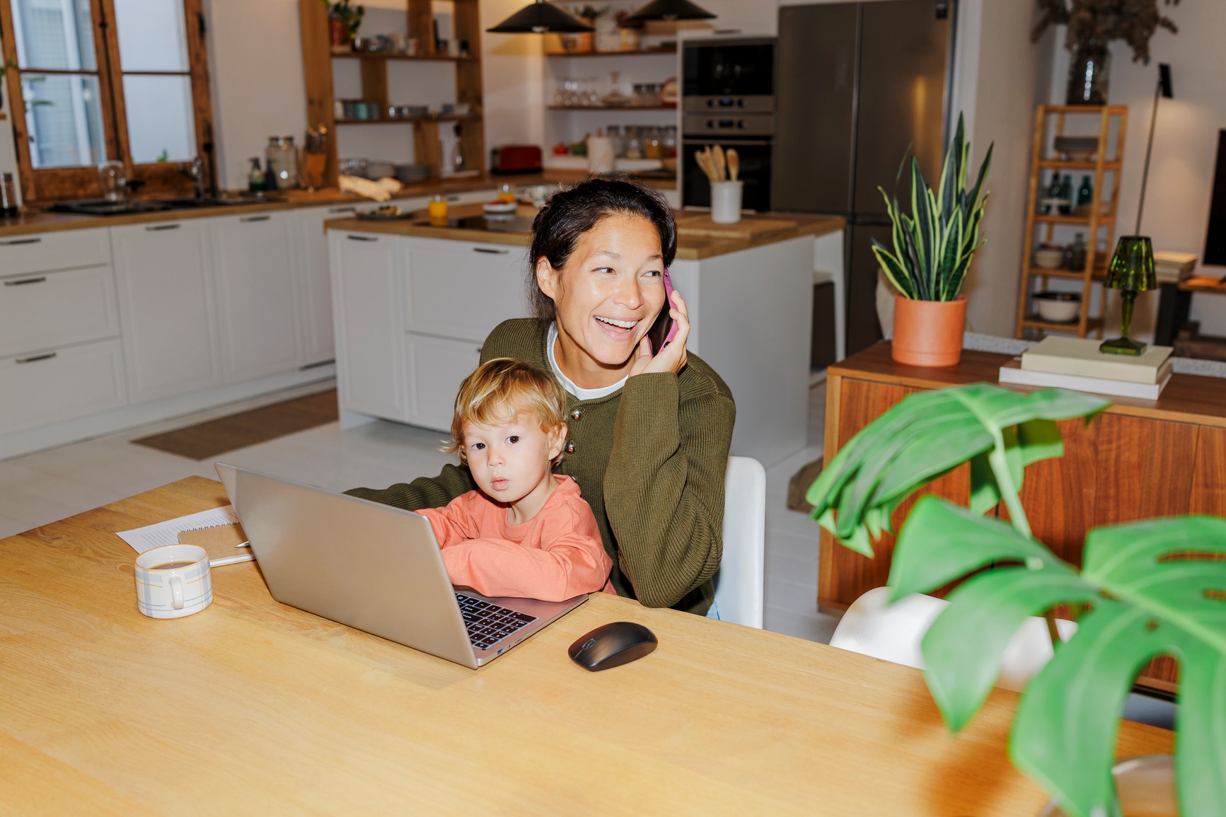 Mom on a work call while her toddler sits at the laptop